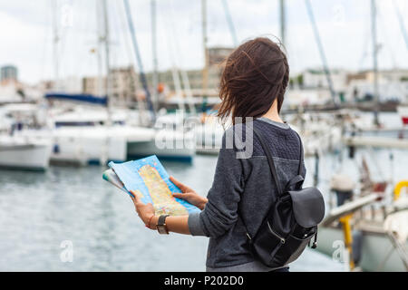 Attractive young female tourist with map exploring new city on harbor background. Gran Canaria, Spain. Traveling concept Stock Photo