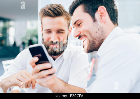 two bearded business men young outdoor using smart phone - wifi technology, social network, multitasking concept Stock Photo