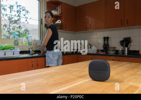 Woman interacting with her smart speaker in the kitchen, background for smart technology concept, AI in modern home environments, personal assistant Stock Photo