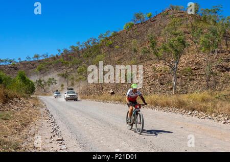 Gibb Challenge 2018 cyclist riding a mountain bicycle and 4 wheel drive support vehicles on a dirt road El Questro Station Kimberley WesternAustralia Stock Photo
