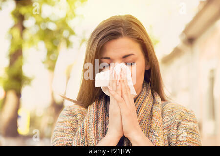 Woman with allergy symptoms blowing nose Stock Photo