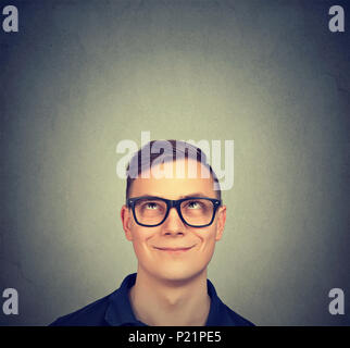 Portrait of a thoughtful man smiling looking up isolated on gray Stock Photo