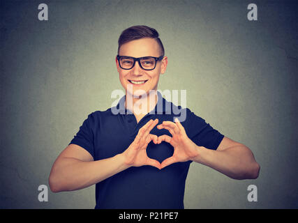 Portrait of happy handsome man in glasses making heart with fingers. Stock Photo