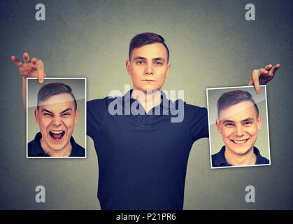 Serious man holding two different face emotion masks of himself Stock Photo