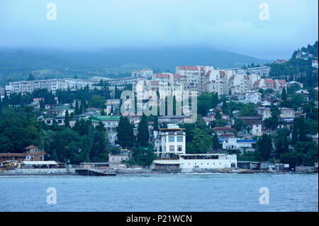 View of the resort town Gurzuf: sea front, beach, buildings and mountains in the fog. June 10, 2017. Gursuf, Crimea Stock Photo