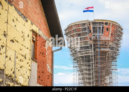 A view of the Vukovar water tower under reconstruction with a house damaged in war in Vukovar, Croatia. The water tower is a symbol of the city suffer Stock Photo