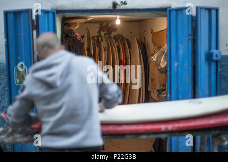 Morocco, Taghazout, man waxing his surfboard Stock Photo