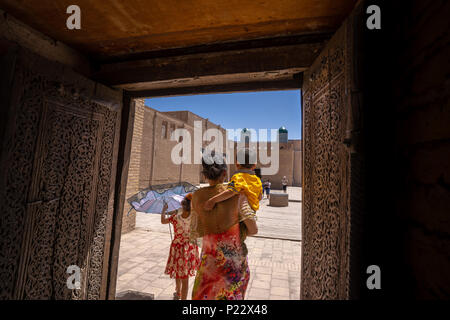 Mother and childs with traditional dress in the sunny inneryard of the kunya ark in Khiva Stock Photo