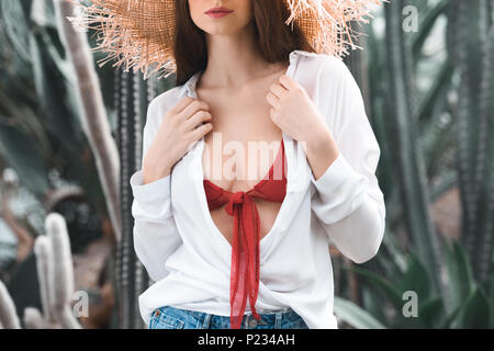 cropped view of girl in summer outfit and straw hat posing in tropical garden Stock Photo