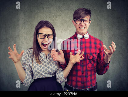 Stressed desperate angry couple screaming standing close to each other on grunge wall background Stock Photo