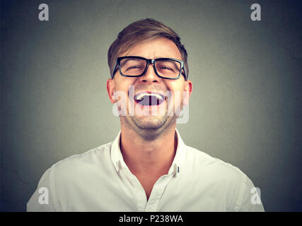 Causal young man in white shirt and black glasses laughing from humorous joke. Stock Photo