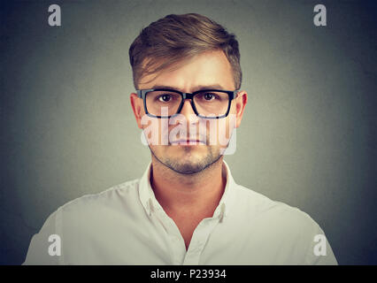 Closeup of young man in white shirt and black glasses looking seriously at camera being professional. Stock Photo