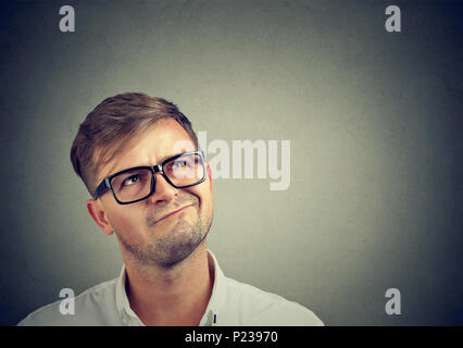 Handsome man in black eyeglasses thinking skeptical and looking up in disbelief. Stock Photo