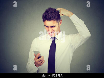 Clueless confused business man having troubles with his smartphone. Complicated technology concept Stock Photo