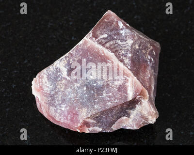 macro shooting of natural mineral - raw pink Flint stone (Chalcedony) on black granite from Ural Mountains Stock Photo