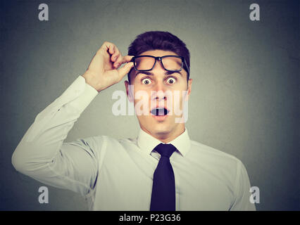 Wow! Surprised young handsome man with opened mouth taking off glasses Stock Photo