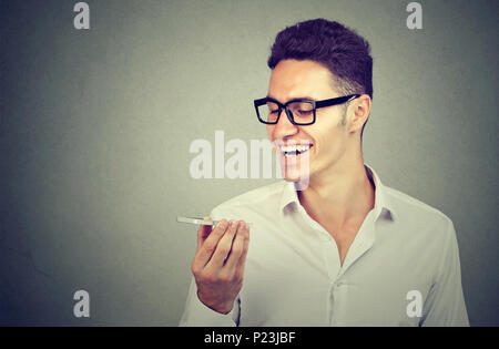 Man using a smart phone voice recognition function on line isolated on gray wall background Stock Photo