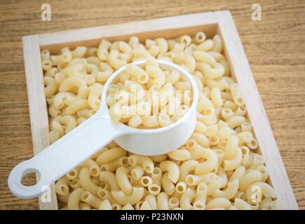 Food and Cuisine, Uncooked and Dried Elbow Macaroni or Gomiti Pasta in Plastic Measuring Cup. Stock Photo