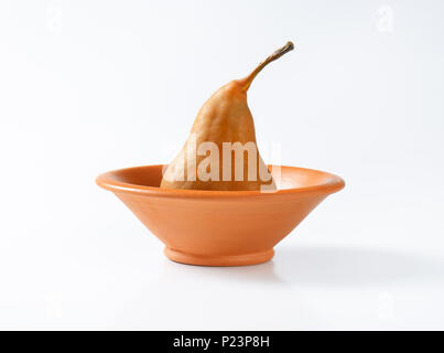 ripe bosc pear in terracotta bowl Stock Photo