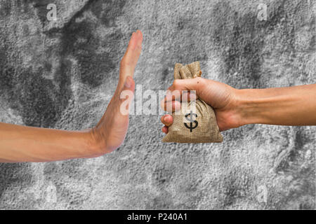 A hands holding money bag and rejecting hand to receive money of another person on concrete wall background. Conceptual stop corruption. Corruption re Stock Photo