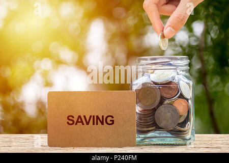 Saving and invest money concept. Conceptual hand putting coins into bottle on nature background. Business investment growth concept. Investing and int Stock Photo