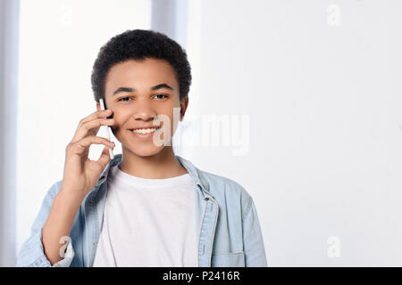 smiling african american teenager talking by smartphone at home Stock Photo