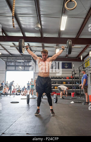 Male or man competing in a CrossFit fitness challenge competition by dead lifting weights inside a gym in Montgomery Alabama, USA. Stock Photo