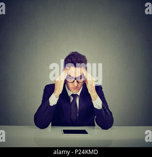 Stressed business man sitting at desk with tablet computer Stock Photo