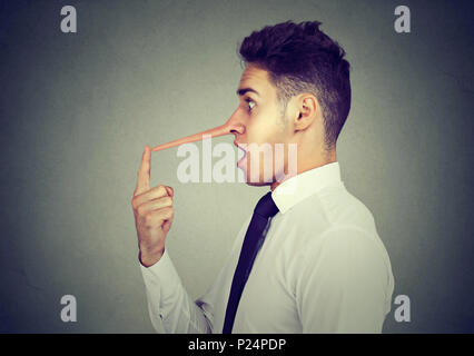 Business man with long nose isolated on grey wall background. Liar concept. Stock Photo