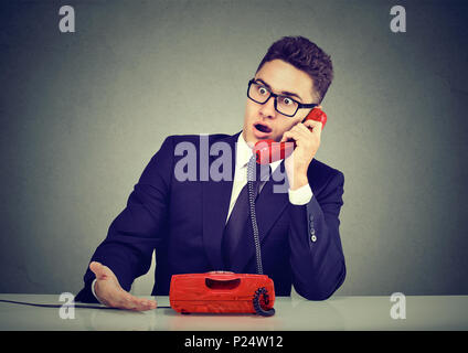 Shocked disgusted young man receiving bad news over the phone Stock Photo