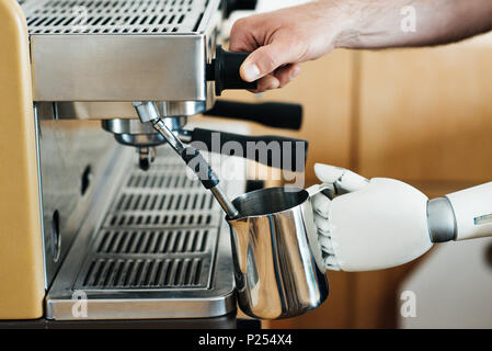 close-up view of robotic arm and human hand preparing coffee in coffee machine Stock Photo
