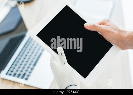 close-up view of human hand and robotic arm holding digital tablet with blank screen Stock Photo