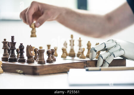 close-up view of person and robotic arm playing chess Stock Photo