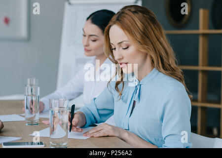 selective focus of businesswomen making notes at workplace in office Stock Photo