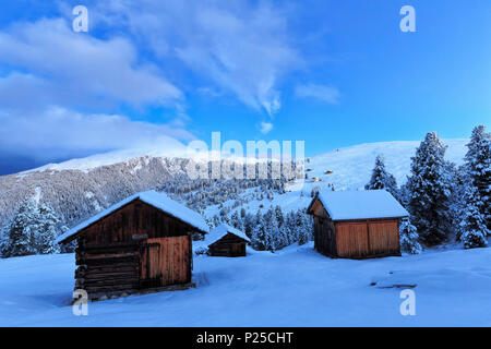Old snow-covered huts during twilight. Erbe Pass, Funes Valley, South Tyrol, Dolomites, Italy Stock Photo