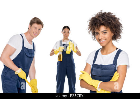 portrait of cheerful multiethnic cleaners in uniforms looking at camera isolated on white Stock Photo