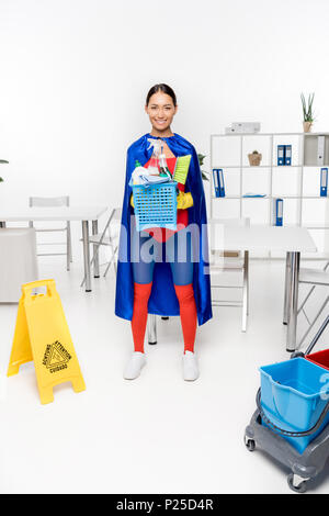 happy beautiful asian superhero cleaner holding box with cleaning equipment and smiling at camera Stock Photo
