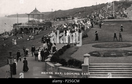 . English: A photograph by Frederick Christian Palmer (d.1941), of the promenade passing Kings Hall (built 1904), at Herne Bay, Kent, England, in the pre-First World War years of the 20th century. Fred C. Palmer worked at Herne Bay from 1903 to 1920, principally from his Tower Studio. The bandstand (seen on the upper part of the hall), does not exist today, although the upper enclosure railings do. To the right of the bandstand is a tiered platform for audience seating. The columned stone wall and steps edging the gardens have been replaced by bollards of cast iron and wood. The path below the Stock Photo