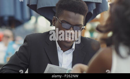 Afro-american businessman with his colleague reading menu in restaurant Stock Photo