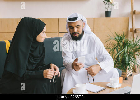 handsome muslim man showing smartphone to woman Stock Photo
