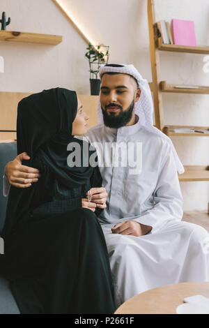 loving muslim couple sitting on sofa and embracing Stock Photo