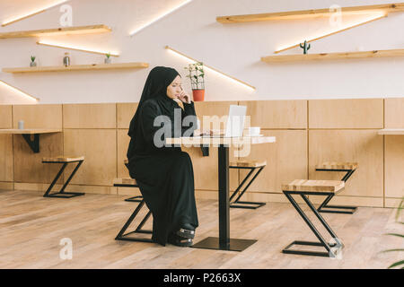 beautiful young muslim woman using laptop in cafe Stock Photo