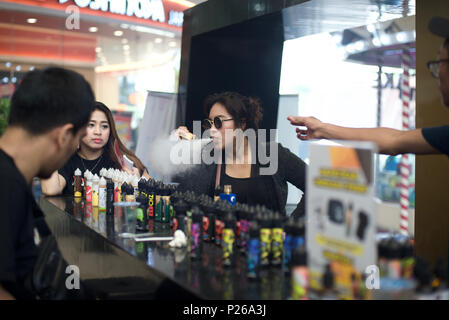 A woman exhales vapor while shopping at an e cigarette liquid stall