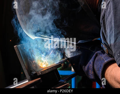 Man tig welding steel plates with brilliant bright white star burst blooms of lights Stock Photo