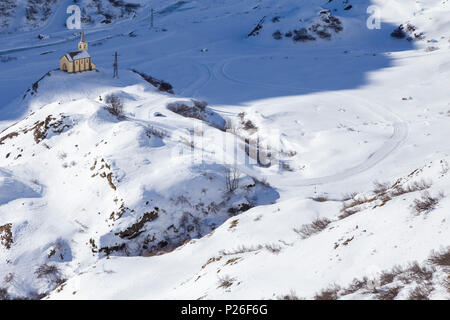 View of the church and town of Riale in winter from the road to the Maria Luisa refuge and the high Formazza Valley. Formazza, Valle Formazza, Verbano Cusio Ossola, Piedmont, Italy. Stock Photo