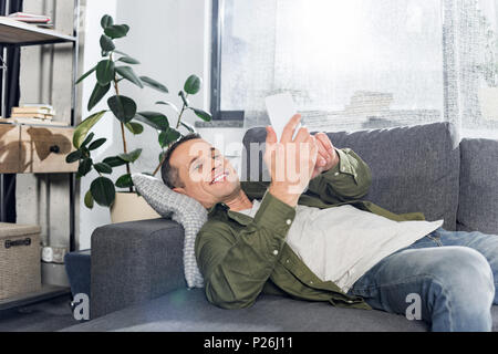 man using smartphone while laying on couch Stock Photo