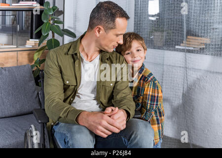 portrait of little son and father in wheelchair at home Stock Photo