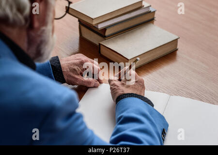 cropped image of senior lecturer writing something in notebook Stock Photo