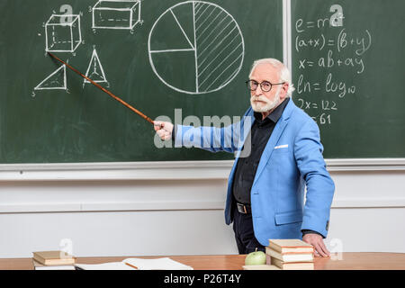 grey hair professor pointing on something with wooden pointer Stock Photo