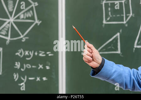 cropped image of senior professor pointing on something with pencil on blackboard Stock Photo